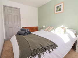 Un dormitorio con una cama, un aparador de madera, una puerta y un cuadro en la pared.