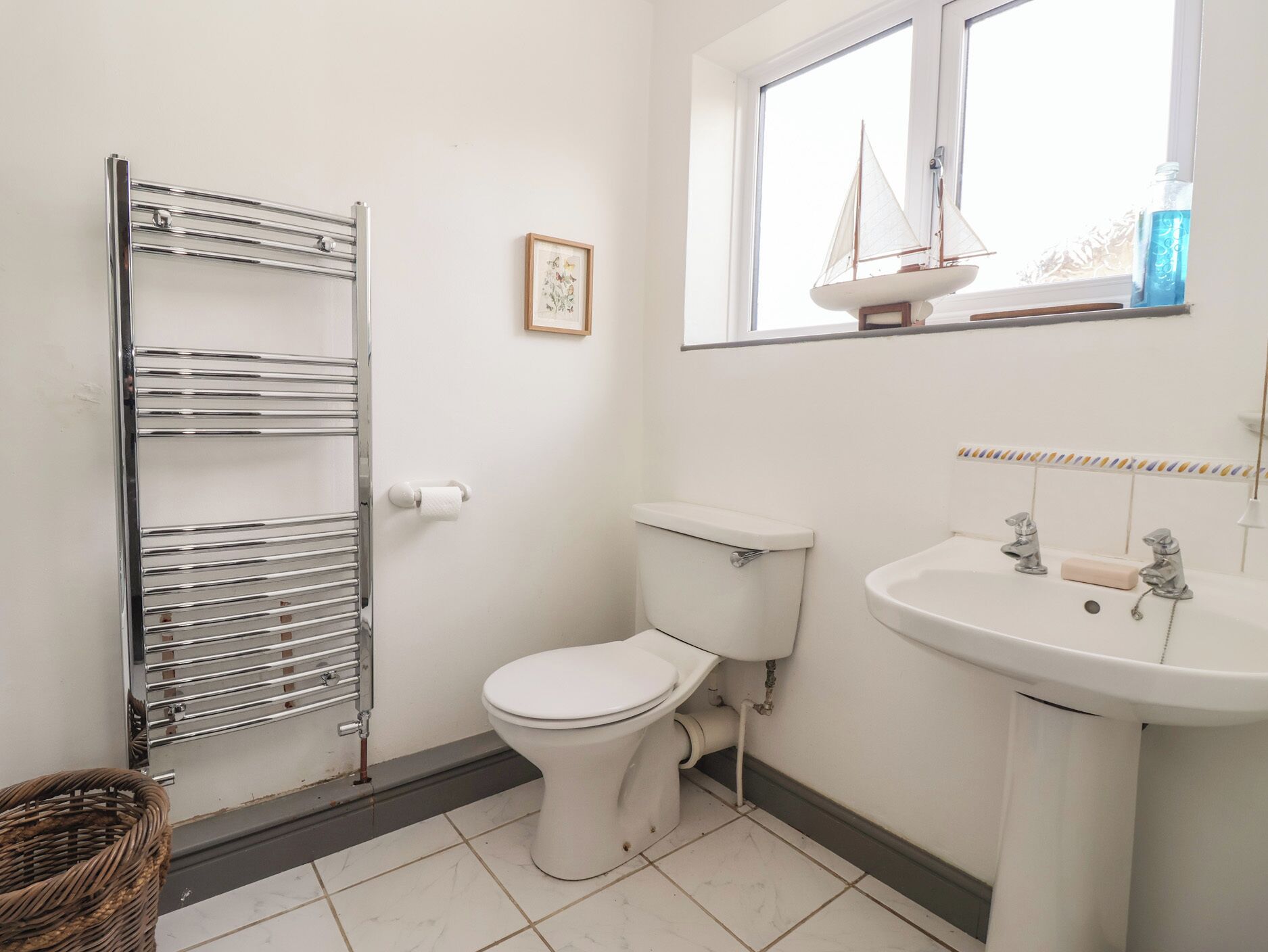 A bathroom with a toilet, sink, and towel rack.