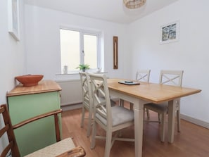 Un comedor con una mesa y sillas de madera, un ventanal con vistas y un radiador.