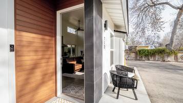 A modern house with a wooden exterior, a visible number '712' on the wall, and a black chair outside.