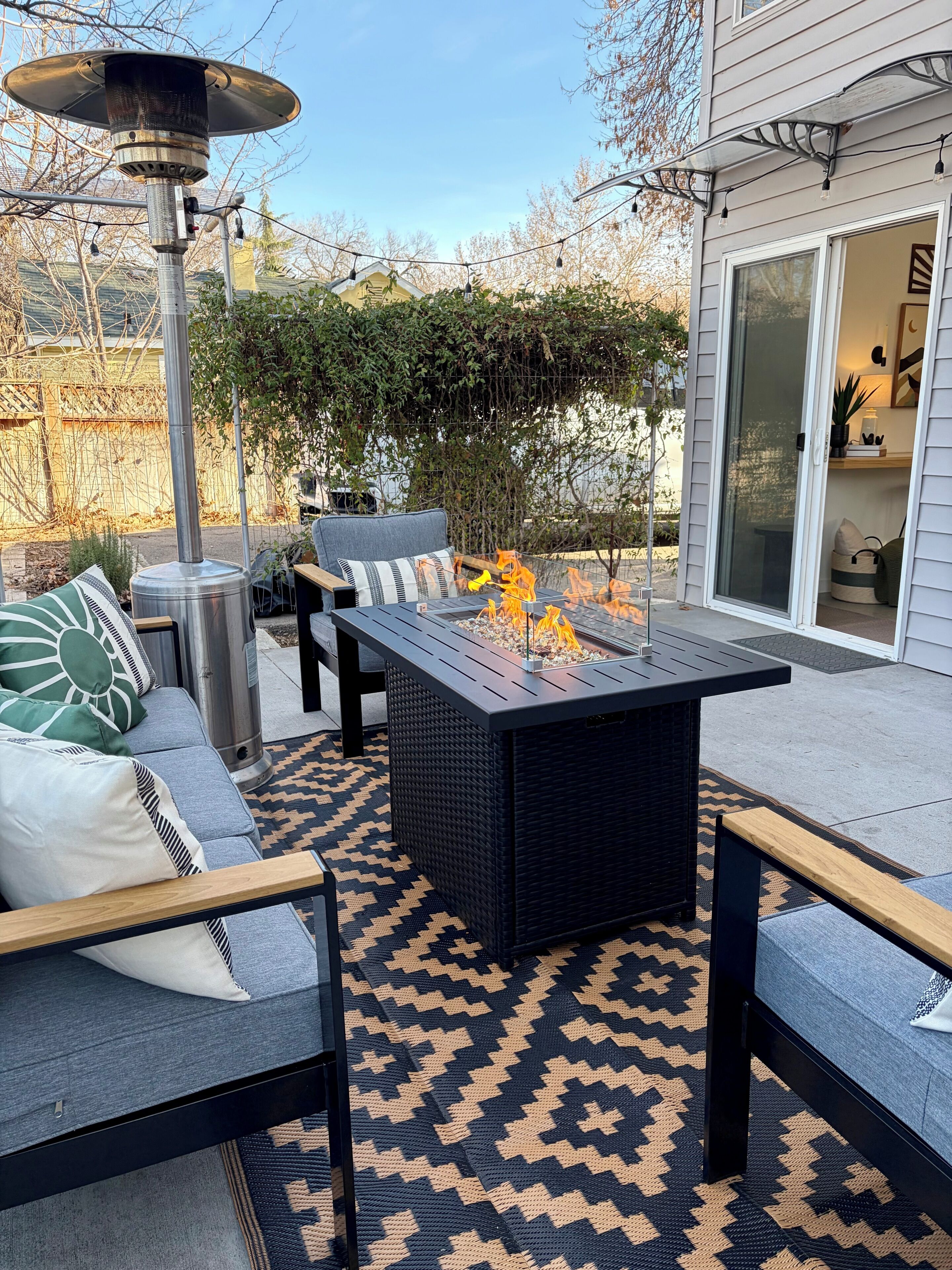 Eine Terrassenausstattung mit Feuerstelle, Sitzgelegenheiten und einer Pergola.