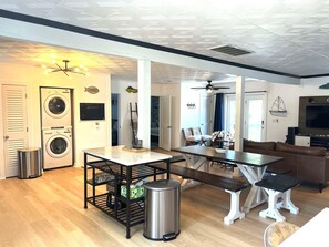 Un espacio habitable moderno con comedor, sofá, televisor y cuarto de lavado.