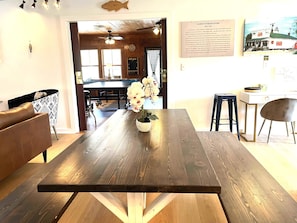 A dining area with a wooden table, chairs, and a potted plant. - Albert's By The Lighthouse: Historic Home with Modern Updates (Ocracoke)