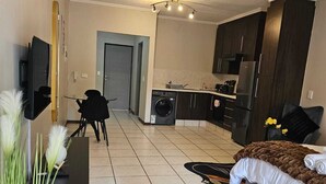 Un appartamento moderno con zona giorno, angolo cottura e camera da letto.