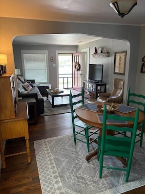 A living room with a sofa, coffee table, and chairs. There is a fireplace and a television.