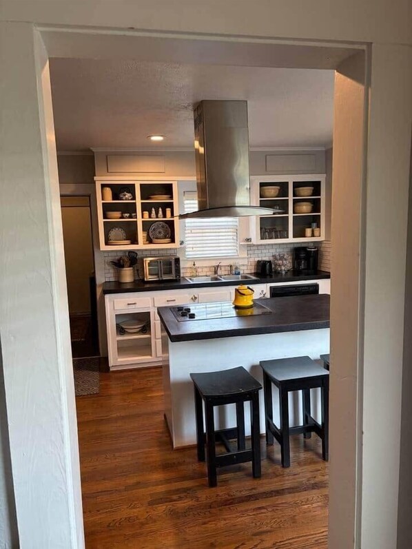 A kitchen with white cabinets, a black countertop, and a yellow kettle.