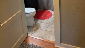 A bathroom with a toilet, sink, and shower curtain. - The Gates House (Brady)