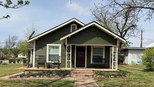 A single-story house with a front porch, a small front yard, and a visible driveway. - The Gates House (Brady)