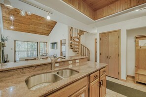 Una cocina moderna con encimera de granito, pileta de acero inoxidable, armarios de madera y una escalera en espiral.