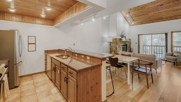 A modern kitchen with wooden cabinets, a central island, and a dining area with chairs.