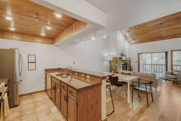 Una cocina moderna con armarios de madera, una isla central y una zona de comedor con sillas.