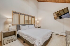 A bedroom with a bed, bedside tables, lamps, a TV, and a mirror.