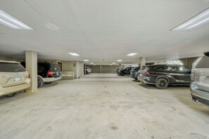 A multi-level parking garage with several cars parked, concrete floors, and overhead lighting.