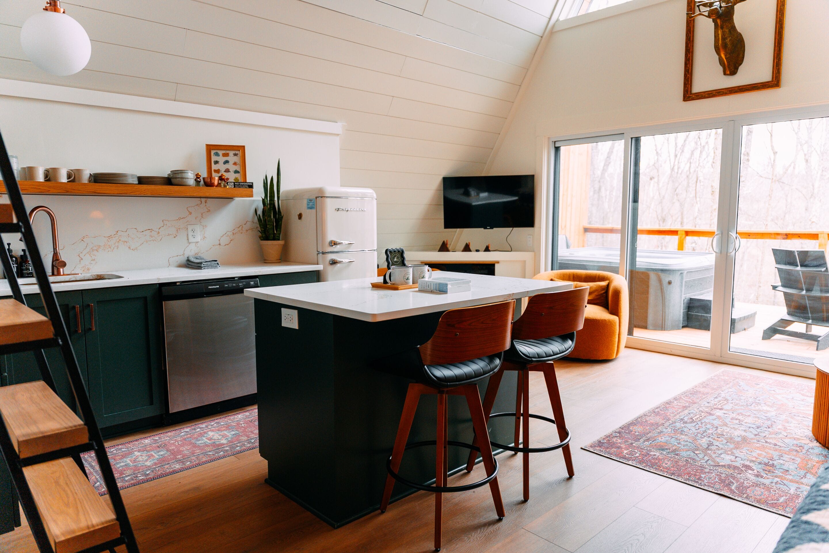 Een moderne keuken met een centraal eiland, barstoelen, een vaatwasser en een televisie.