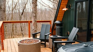 Une terrasse en bois avec des sièges d’extérieur, un foyer et un jacuzzi.