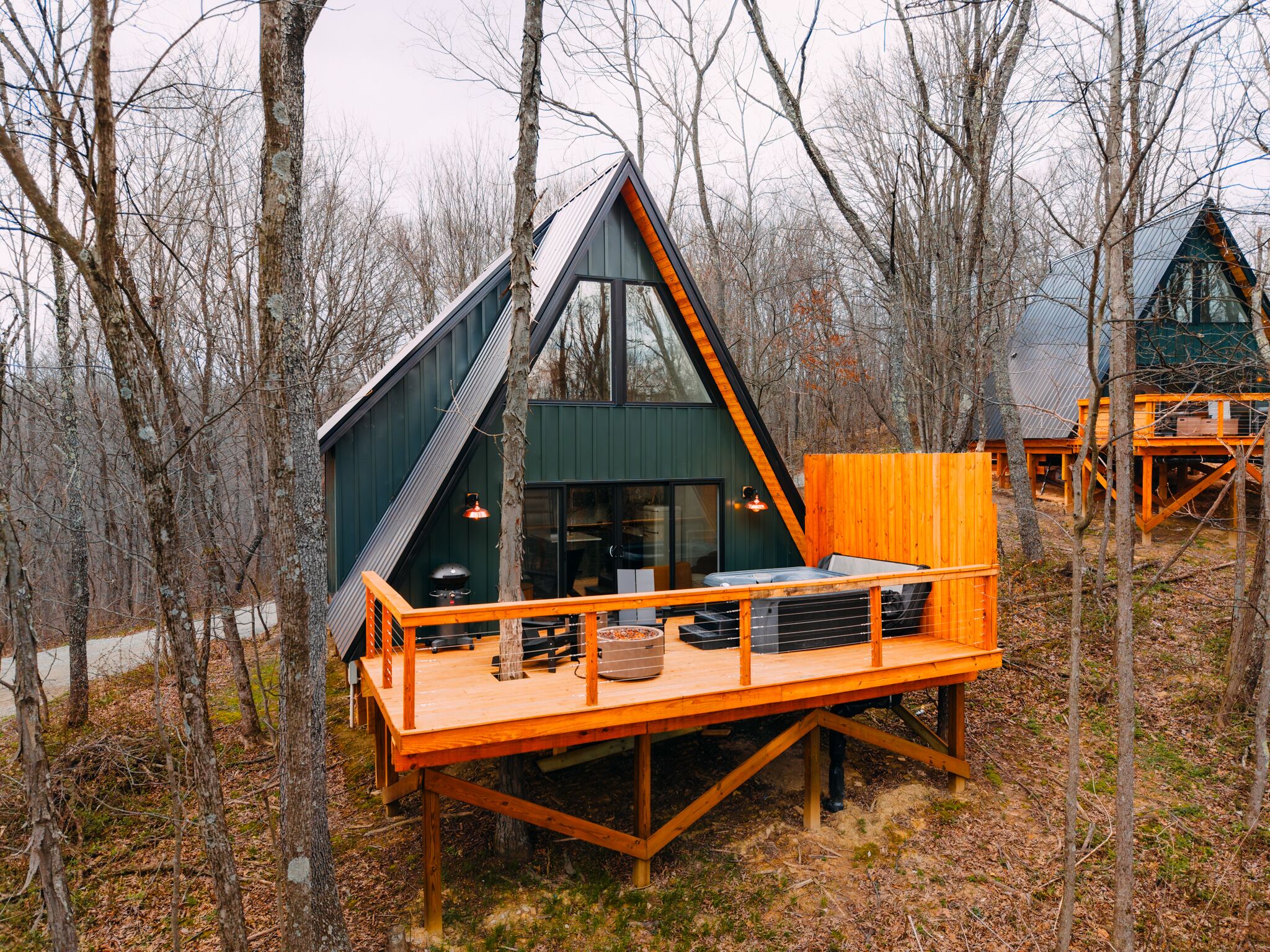 A cabin with a sloped roof, a deck with outdoor seating, and a large window.