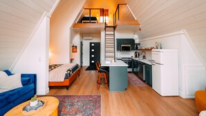 Un appartement de style « loft » comprenant une cuisine, un coin repas et une chambre avec un lit en mezzanine.