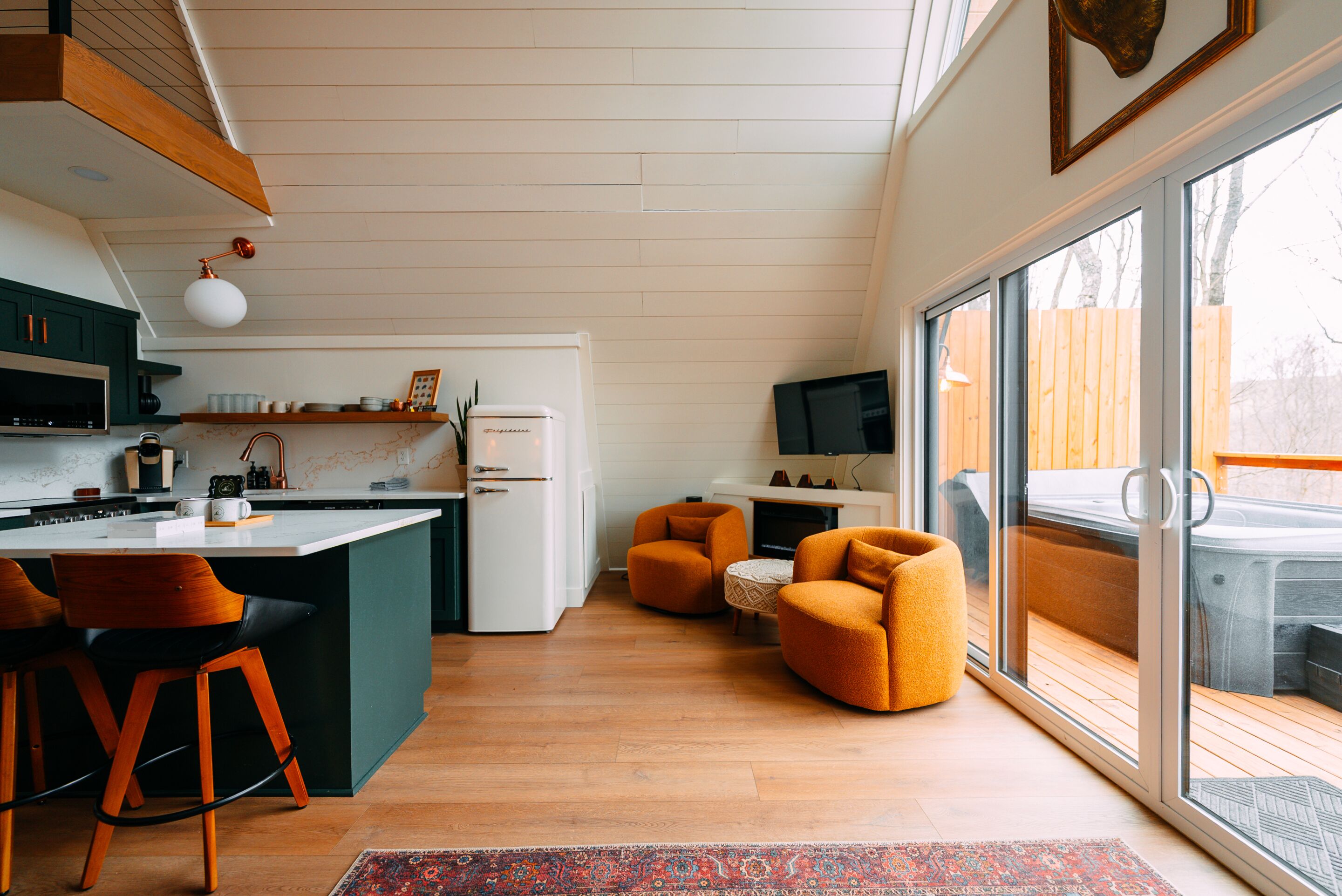 A modern kitchen with a central island, bar stools, and a large sliding glass door leading to an outdoor area.