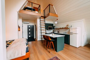 A loft-style apartment with a kitchen, dining area, and a bedroom with a loft bed. - Hickory Hollow | Hocking Hills, Hot Tub, Romantic (McArthur)