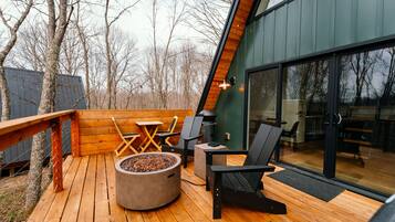 A deck with a fire pit, seating, and a view of the surrounding trees.