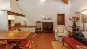 Un accogliente soggiorno con soffitto in legno, un tavolo da pranzo, un divano e una poltrona.