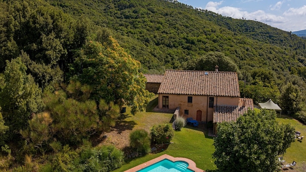 Una casa con piscina, immersa in un paesaggio verdeggiante e colline.