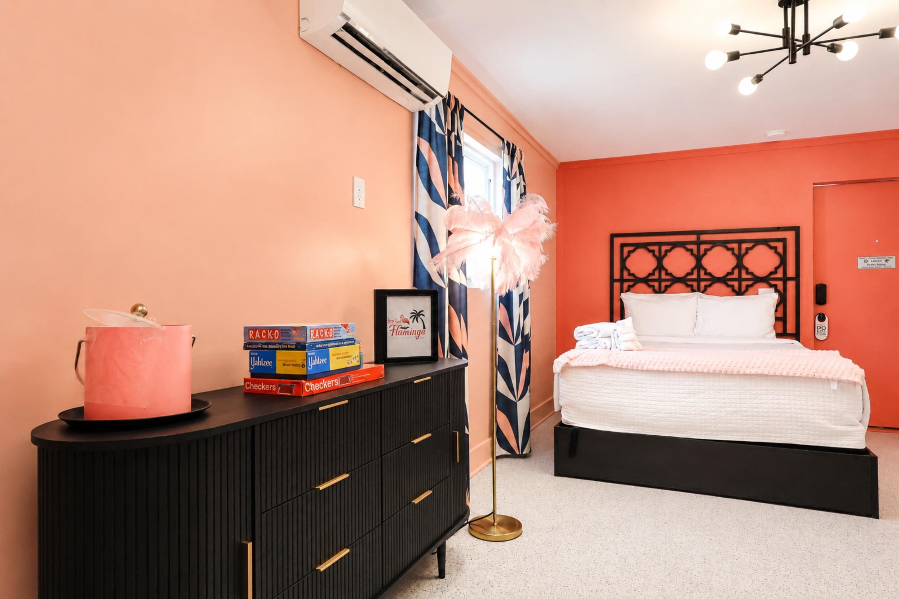 A bedroom with a bed, a dresser, a vanity, and a decorative plant.