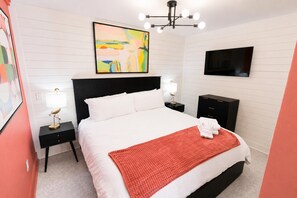 Ein Schlafzimmer mit einem Bett, Nachttischen, einem Fernseher und einem Bild an der Wand.