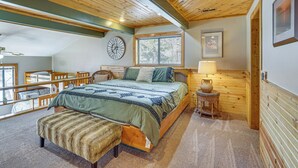 A bedroom with a wooden ceiling, a bed with a green and blue patterned bedspread, a wooden bench, a bedside table with a vase, and a window with blinds. - Private Dual-slip Dock! Lake of the Ozarks Home (Gravois Mills)