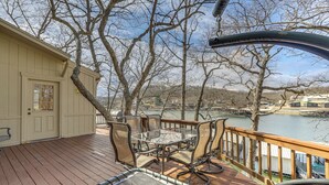 A deck with a glass-top table and chairs, overlooking a body of water and trees. - Private Dual-slip Dock! Lake of the Ozarks Home (Gravois Mills)