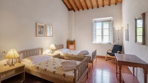 Een kamer met twee bedden, een bureau, een stoel en een raam.