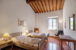 Ein Zimmer mit zwei Betten, einem Schreibtisch, einem Stuhl und einem Fenster.