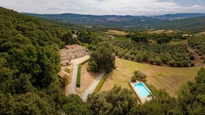 Uma vila com piscina, rodeada por vegetação exuberante e colinas.