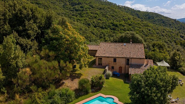 Uma casa com piscina, cercada por uma paisagem verdejante e colinas.