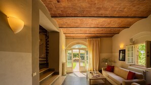 Un interior acogedor con una escalera, un sofá, una mesa y una ventana con vistas.