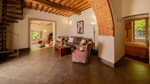 Amplia sala de estar con techo de madera alto, una escalera y vistas a través de una ventana.