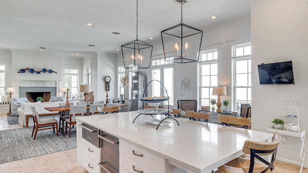 A spacious kitchen with a large island, pendant lights, and a dining area with a fireplace. - On the Beach + Gulf: Luxe Pass Christian Escape (Pass Christian)