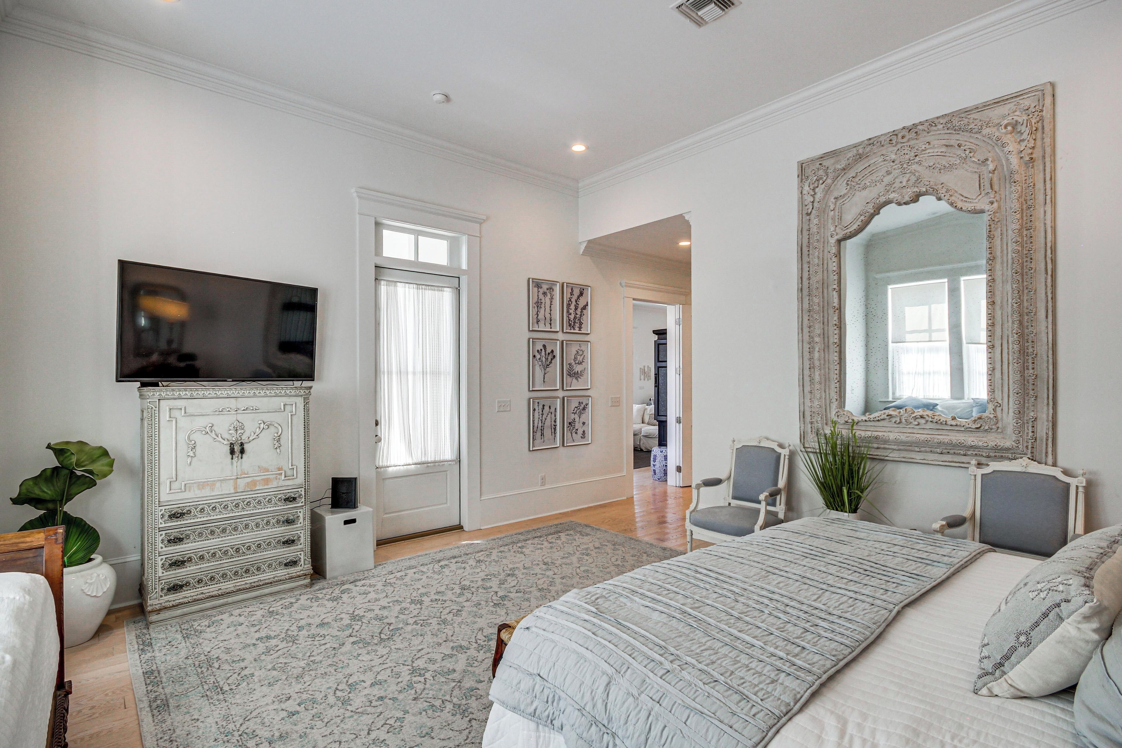 A bedroom with a bed, a dresser, a television, and a large mirror.
