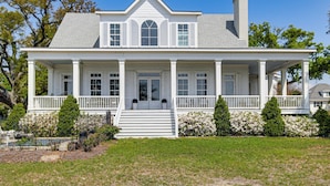 A two-story house with a front porch, a chimney, and a well-maintained lawn. - On the Beach + Gulf: Luxe Pass Christian Escape (Pass Christian)
