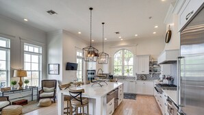 A spacious kitchen with a large island, modern appliances, and ample natural light. - On the Beach + Gulf: Luxe Pass Christian Escape (Pass Christian)