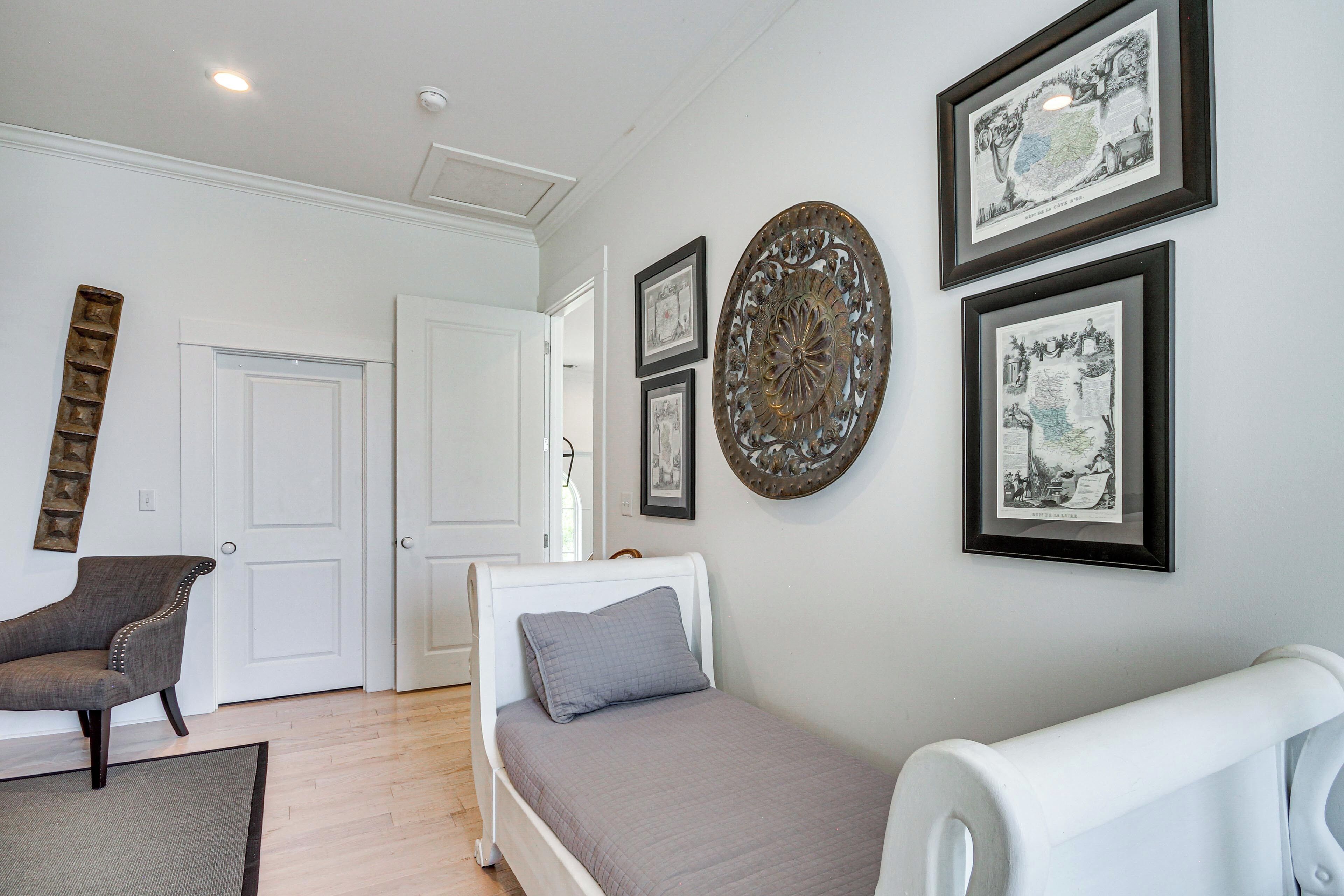 A bedroom with a bed, a chair, and framed artwork on the wall.