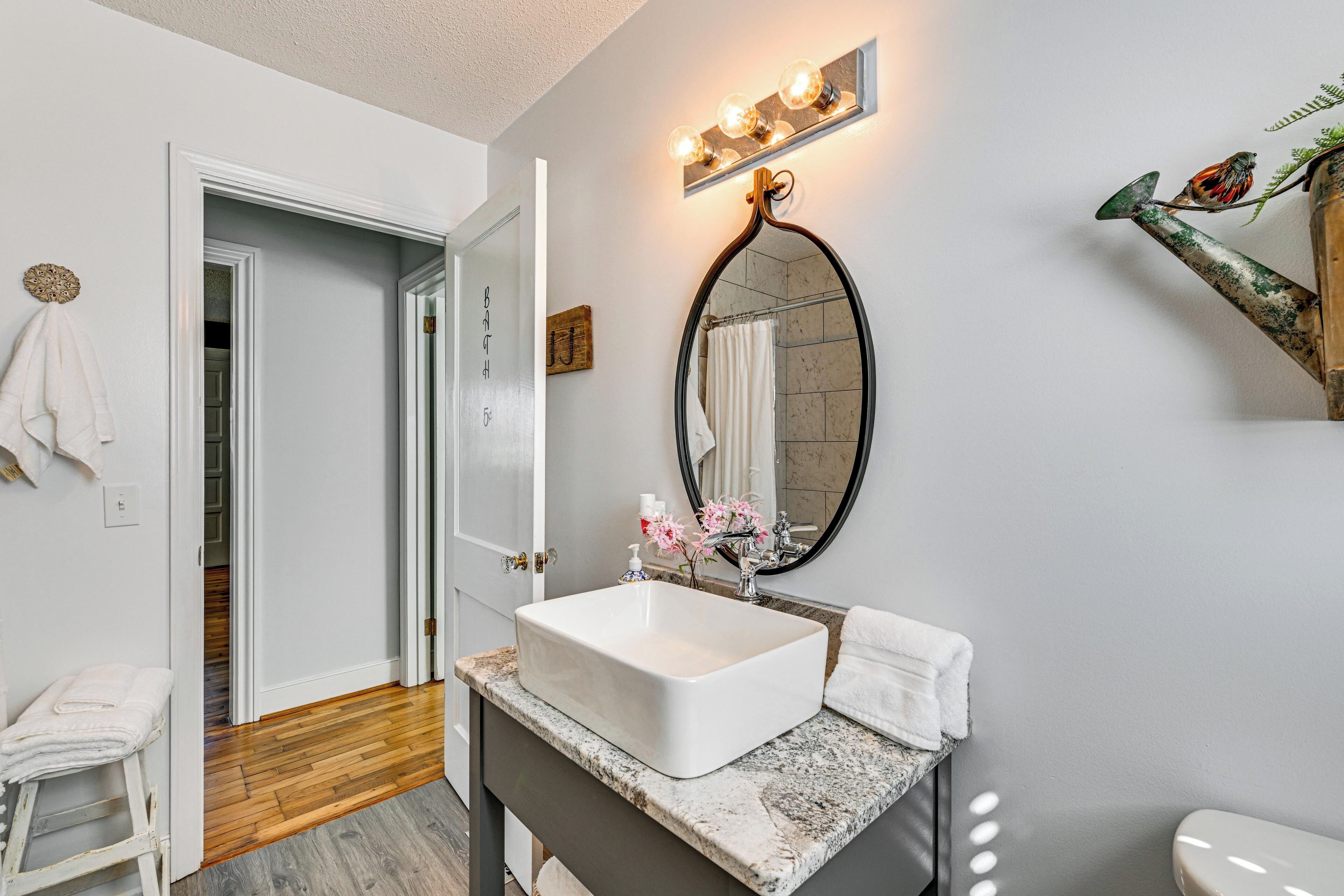 A bathroom with a white sink, a mirror, and a shower.