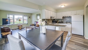 A modern kitchen with white cabinets, a dining area with a dark table, and a ceiling fan. - Cozy Couples Escape in Homewood: Pets Welcome! (Homewood)