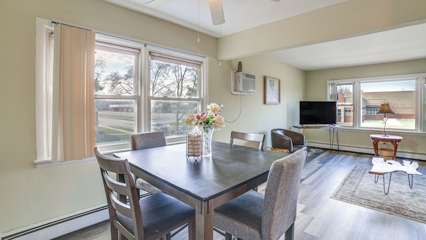 A dining area with a table, chairs, a ceiling fan, a TV, and a window with curtains. - Cozy Couples Escape in Homewood: Pets Welcome! (Homewood)