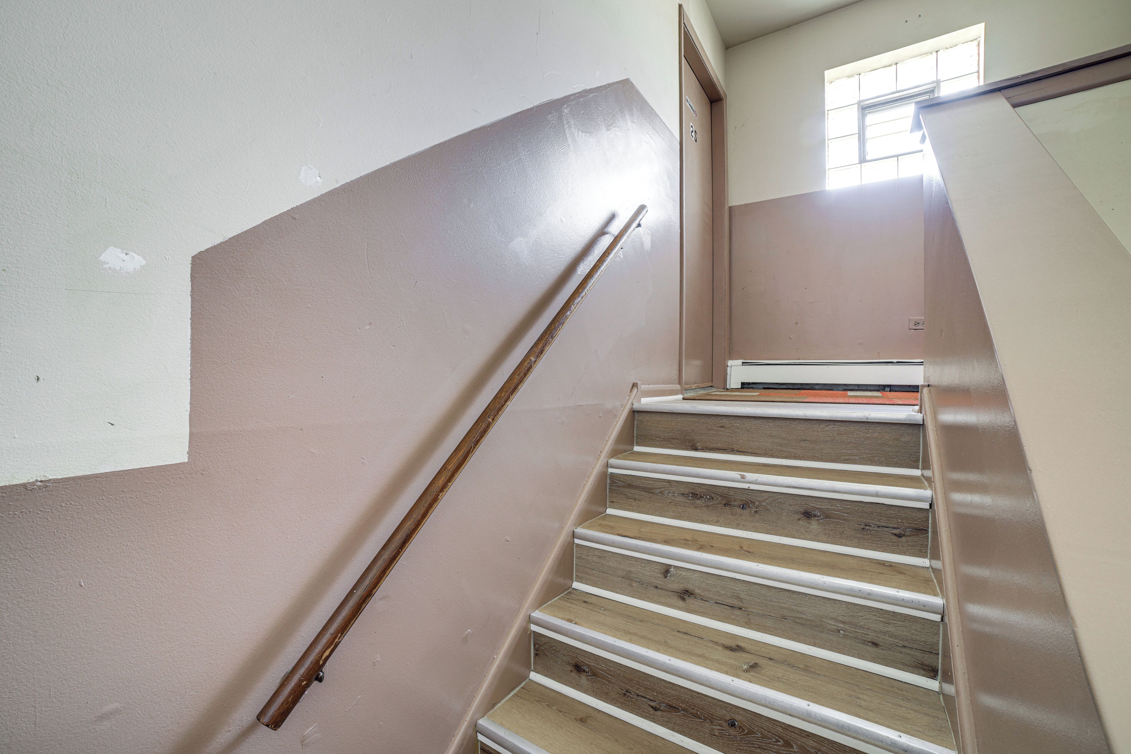 Una escala de fusta amb barana metàl·lica que condueix a un relleny amb una finestra.