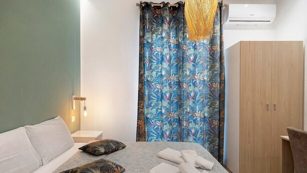 Ein Schlafzimmer mit Bett, Kissen, Kleiderschrank und Vorhang.