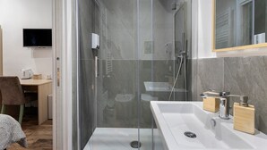 Ein modernes Badezimmer mit einer gläsernen Duschkabine, einem Waschbecken und einem Spiegel.