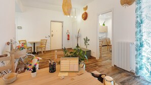 Una habitación con suelo de madera, una mesa con un calendario, sillas, una bicicleta y una planta.