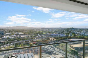 A cityscape with a prominent highway interchange and a distant mountain range. - Windward Inner city Skyline Stay with Pool Access (Bowen Hills)
