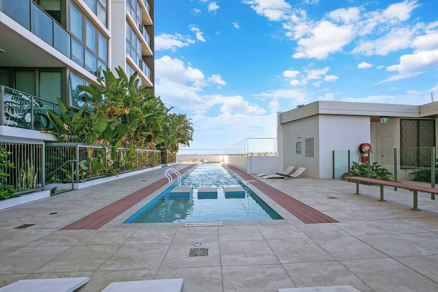 A rooftop pool with a clear view of the city skyline, surrounded by modern buildings and lush greenery.